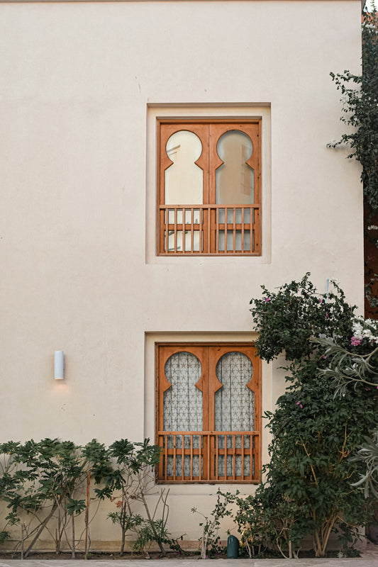 a white building with two windows and a cat sitting in the window
