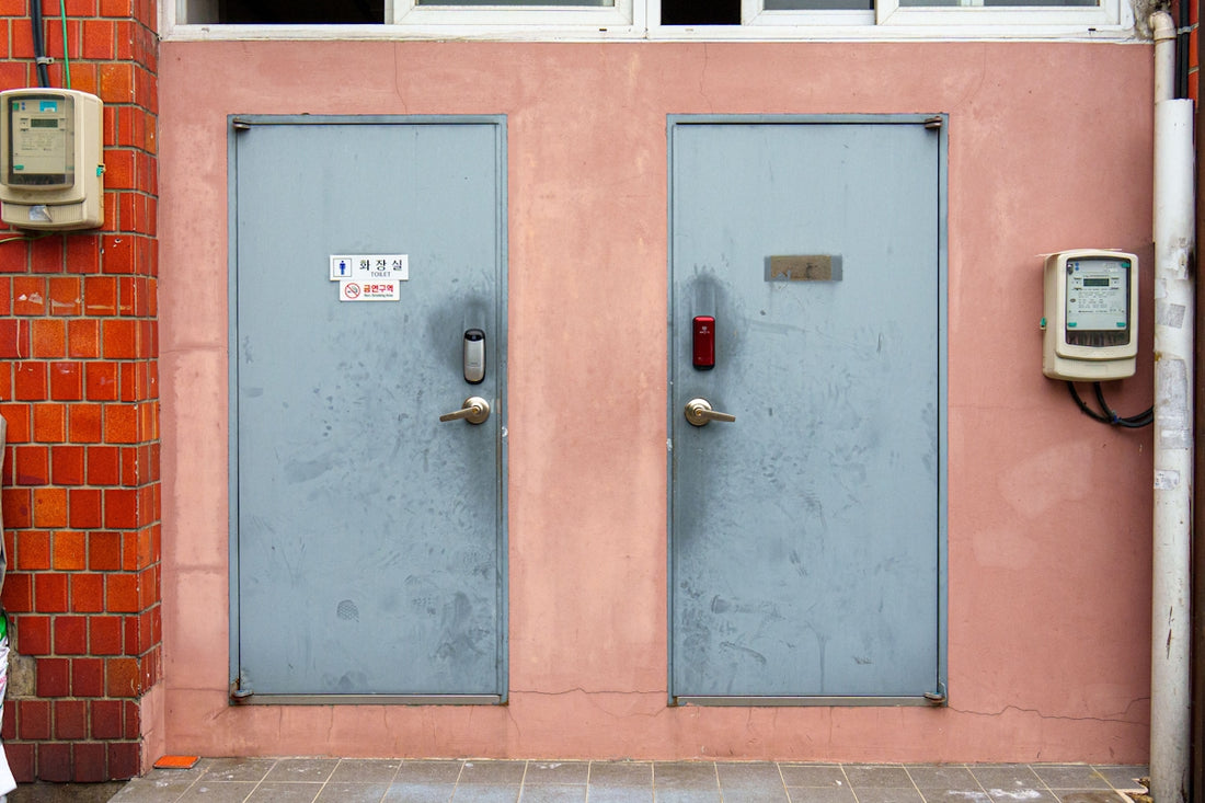 Two gray doors stand against a pink wall.